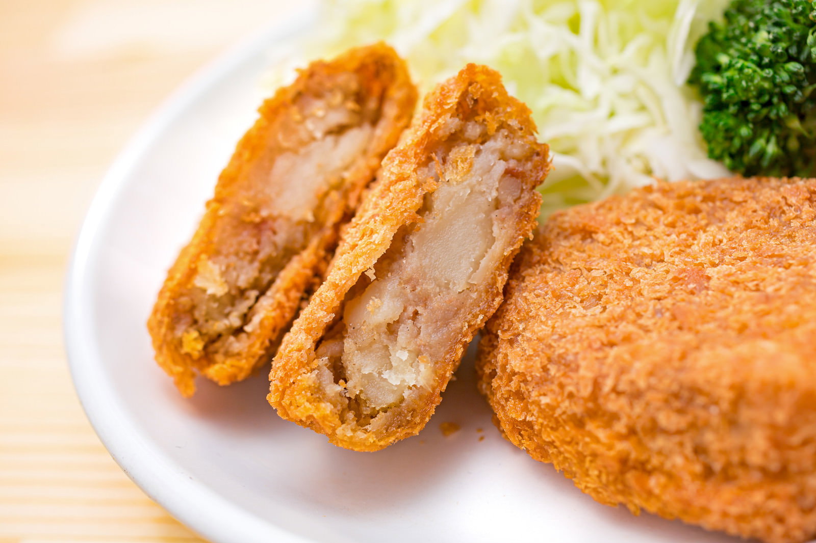 白いお皿に盛り付けられたレンチンしたコロッケと千切りキャベツ