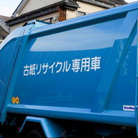 住宅地に停まる古紙リサイクル専用の青いボディの資源回収トラックの写真