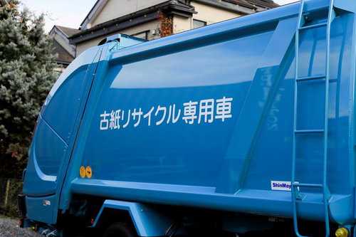 住宅地に停まる古紙リサイクル専用の青いボディの資源回収トラック