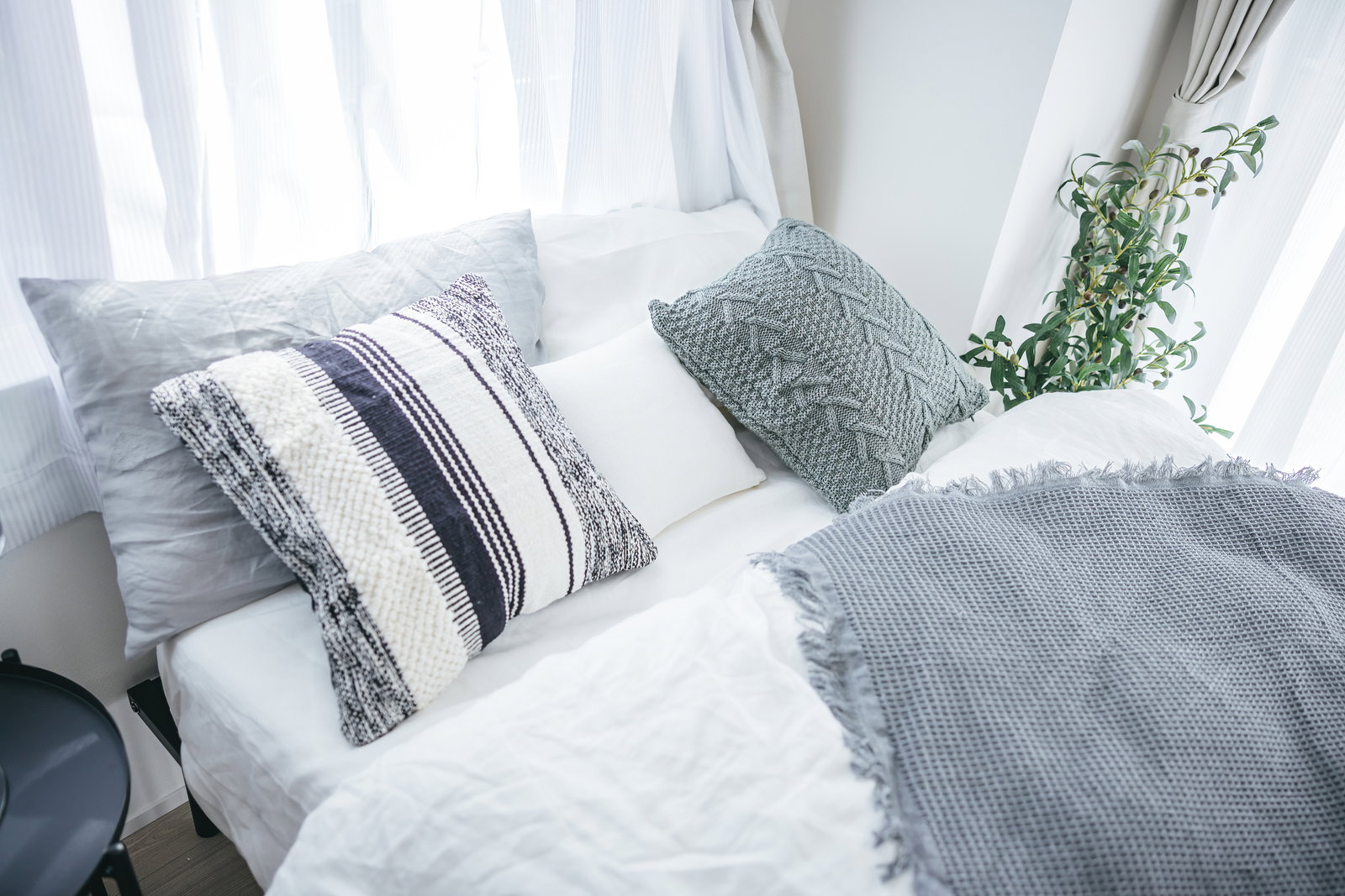 白いベッドに複数の枕とクッションが置かれた寝室