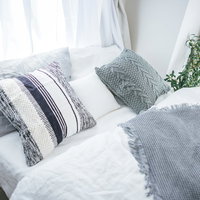 白いベッド上に並ぶ複数の枕とクッション、寝室インテリアの写真