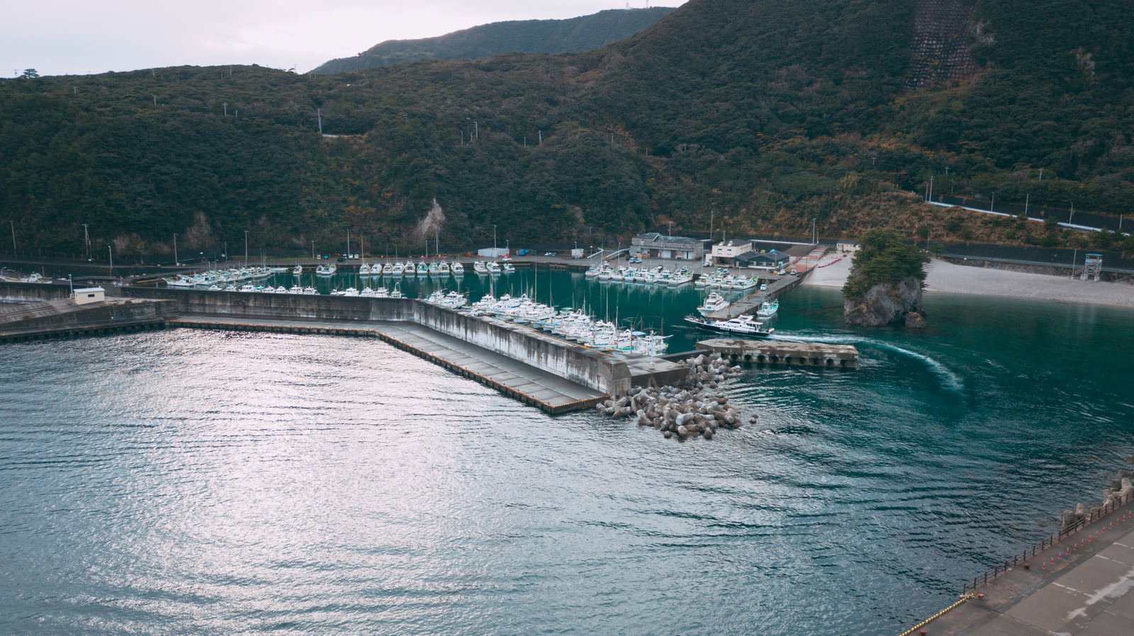 神津島多幸湾の漁港に停泊する白い漁船群とエメラルドグリーンの海