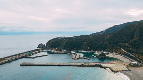 神津島の多幸湾上空から見た漁港と漁船、緑の山々に囲まれた景観