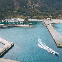 神津島の多幸湾から出港する白い漁船と漁港の風景の写真