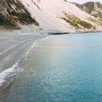神津島の多幸湾海水浴場、エメラルドグリーンの海と波打ち際の写真