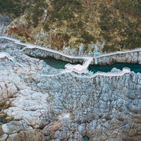 岸壁に設置された木製の遊歩道がある神津島の赤崎遊歩道の写真