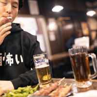 飲み相手がトイレ中に一服する男性の写真