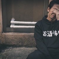 路上の階段で頭を抱える二日酔いの男性、マジでお酒怖いの写真