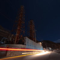 神津本道を走る車の光跡と工場夜景の夜間風景の写真