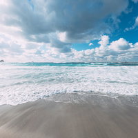 東京の離島・神津島の波打ち際に広がる白い砂浜と青い海の写真