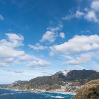 青空と神津島の海岸線と集落の写真