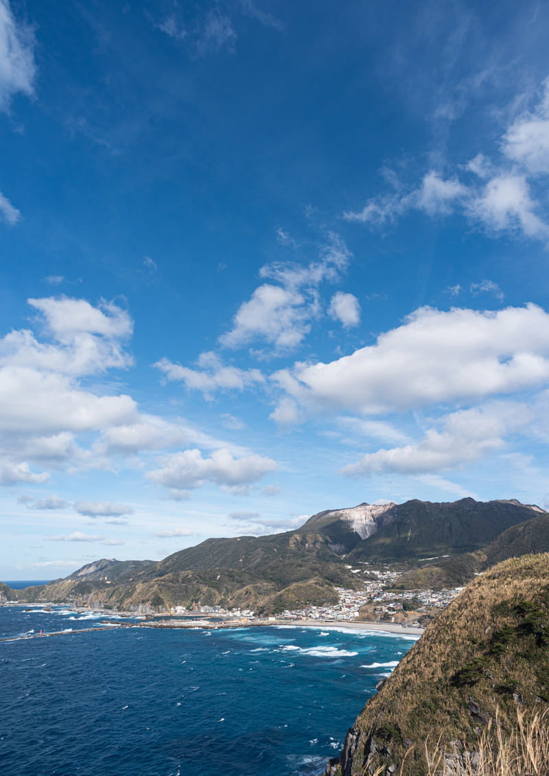 青空と神津島の海岸線と集落