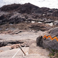 神津島の千両池への険しい登山道、断崖の岩場に設置された階段の写真