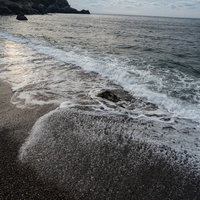 砂浜の波打ち際にザパーと打ち寄せる白い泡立つ波の写真