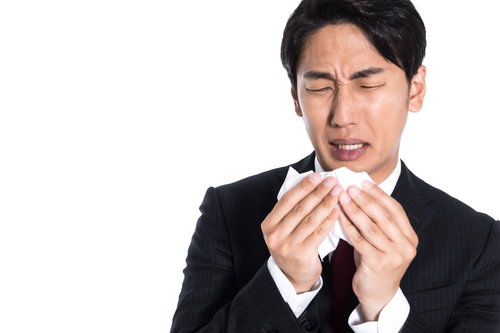 ティッシュで鼻をかんだ後に確認する黒いスーツの男性