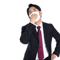 インフルエンザでふらふらの会社員、マスク姿で額を押さえるの写真