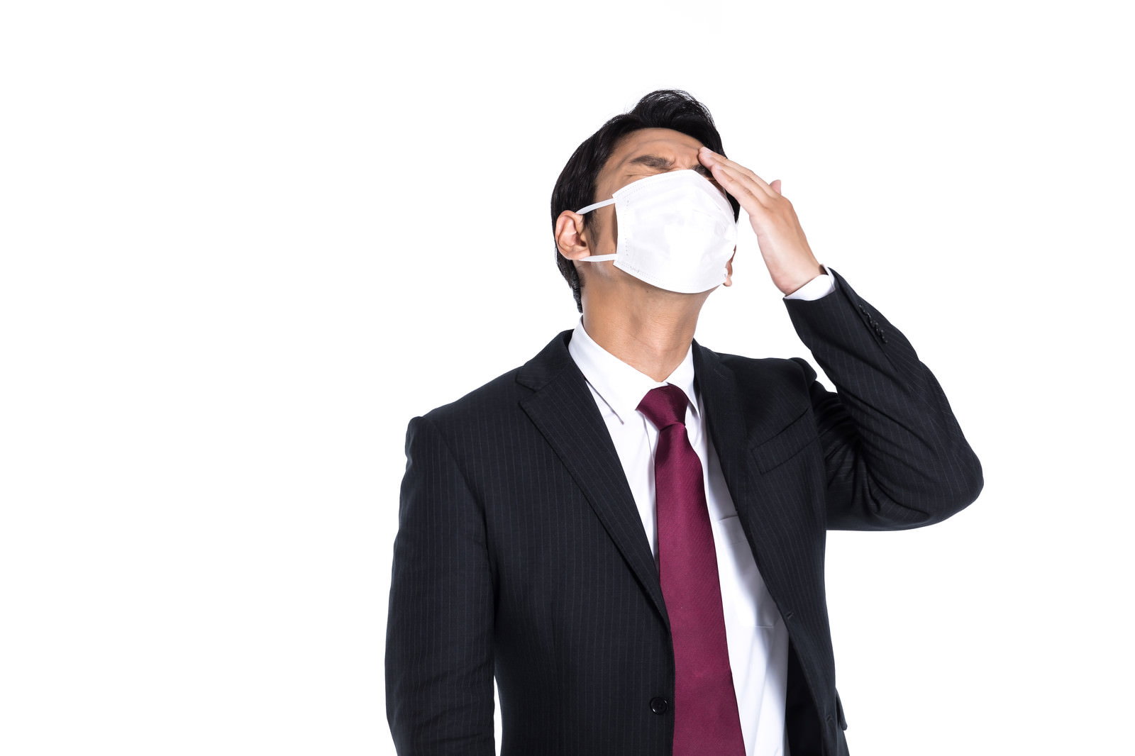 マスクをつけた会社員が頭に手を当てている様子［モデル：大川竜弥］