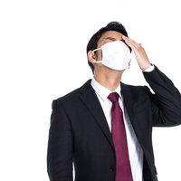 咳は出るし頭も痛くなってきたマスク姿の会社員の写真