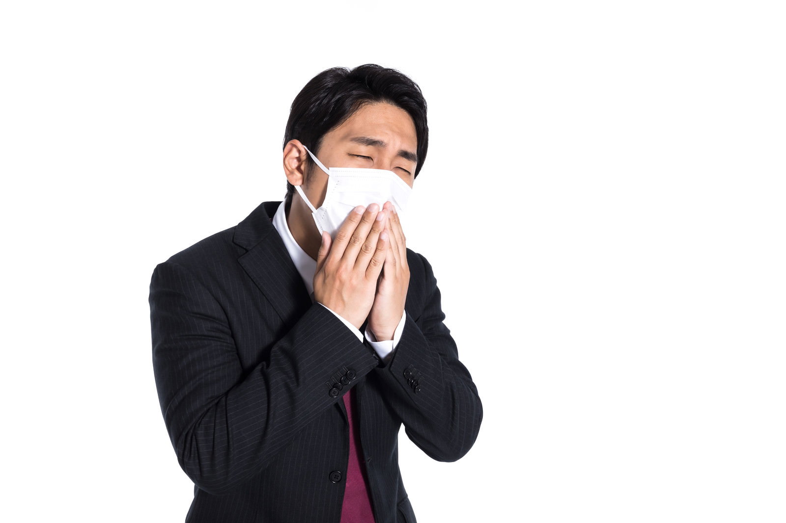マスクを着けて鼻を押さえるスーツ姿の会社員男性［モデル：大川竜弥］