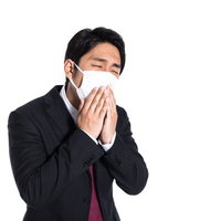 マスク越しに嗅ぐ自分の手が臭い会社員のくしゃみの写真