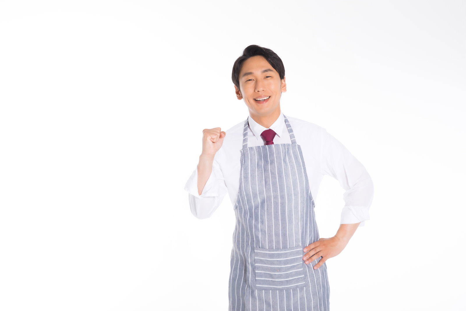 白いシャツにストライプのエプロンを着た男性がガッツポーズをしている［モデル：大川竜弥］