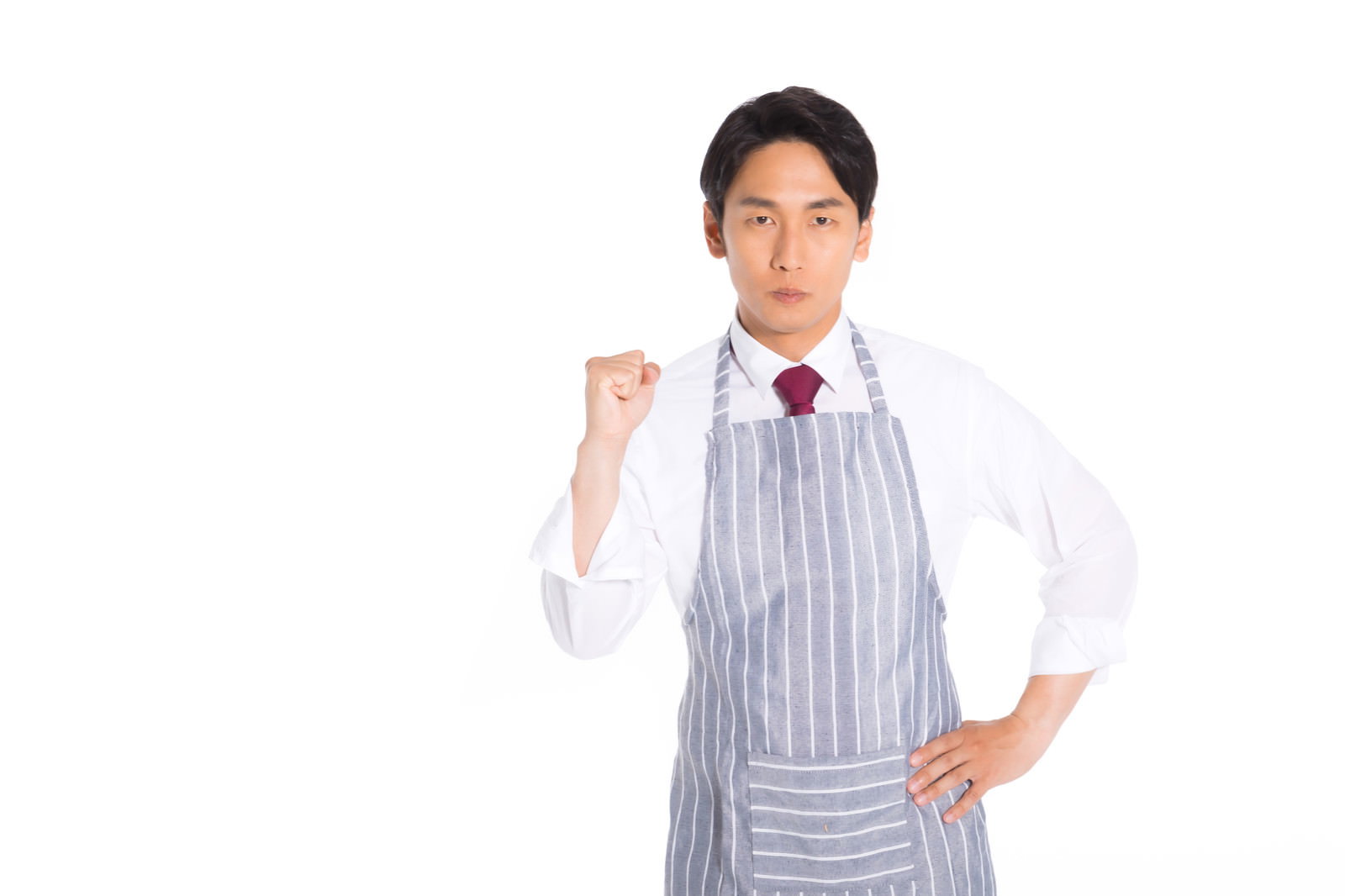 白いシャツにストライプのエプロンを着用した男性がガッツポーズをしている様子［モデル：大川竜弥］