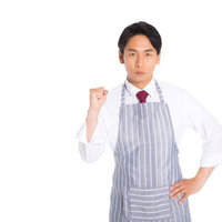 スーツにエプロン姿の男性販売員がガッツポーズの写真