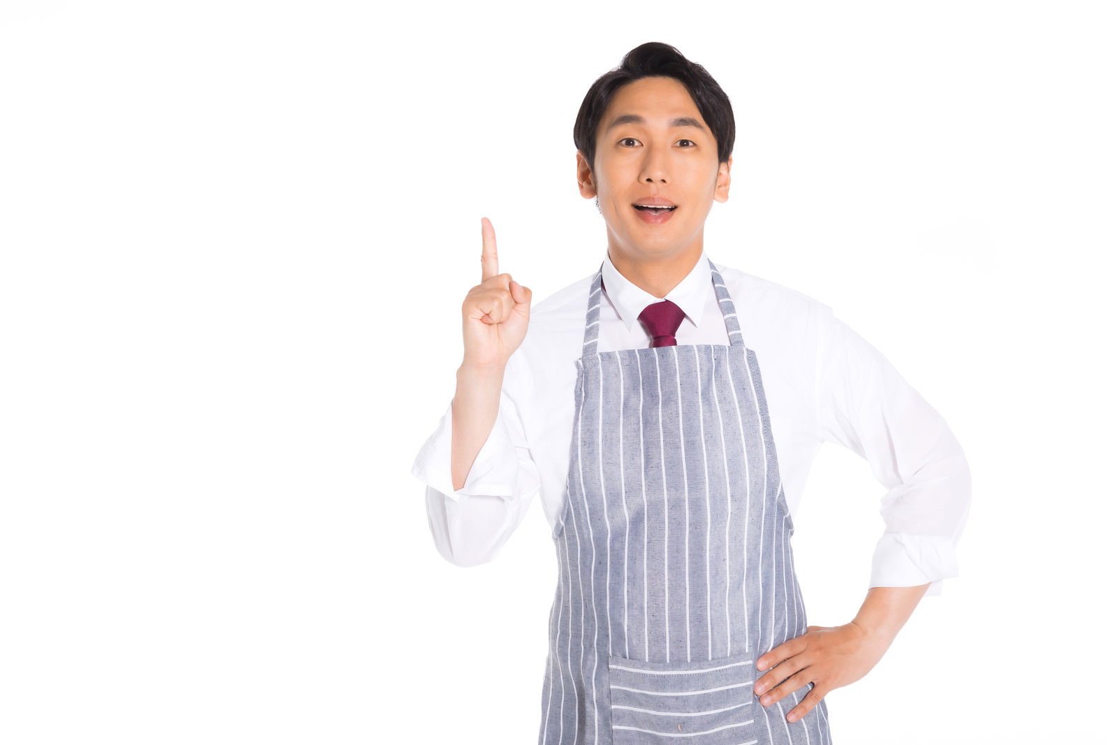 グレーのストライプエプロンを着た男性販売員が右手で上を指差している［モデル：大川竜弥］