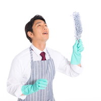 エプロンとゴム手袋で掃除するキレイ好きの男性社員の写真