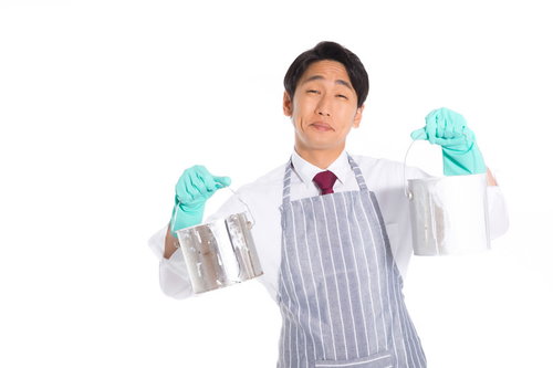 ペンキ缶を両手で持つエプロン姿の営業マン