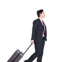 キャリーバッグをゴロゴロ引いて歩く出張中の会社員の写真
