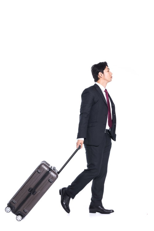 キャリーバッグをゴロゴロ引いて歩く出張中の会社員