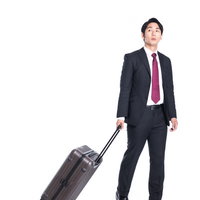 打ち合わせ先へスーツケース持参する会社員の写真