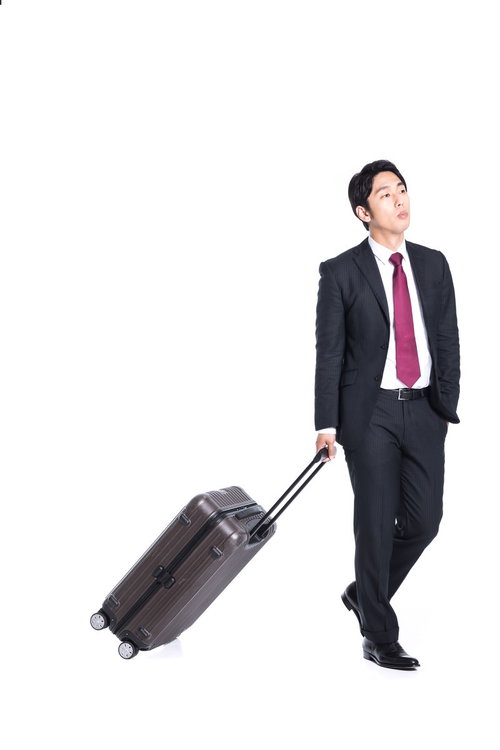 ポケットに手を突っ込みキャリーを引く男性