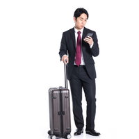 スマートフォンで出張のスケジュール確認をする会社員の写真