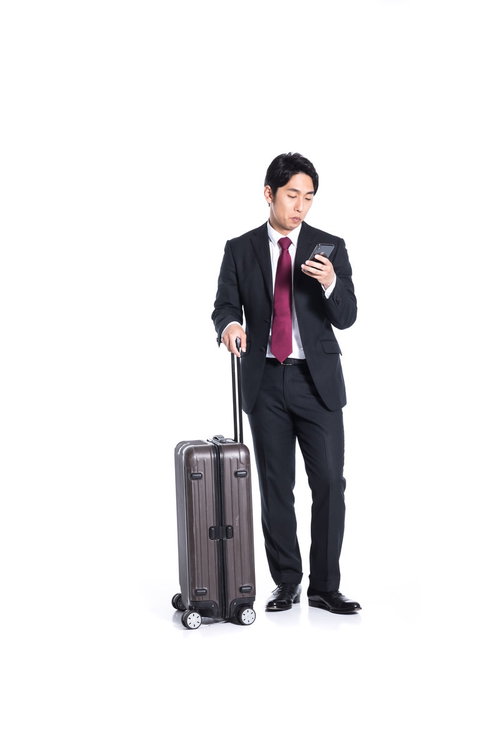スマートフォンで出張のスケジュール確認をする会社員