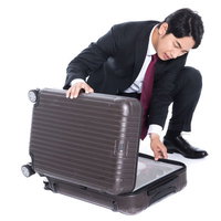 出張中、忘れ物に気づいて困った男性とキャリーケースの写真