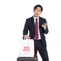 お土産に551の白い紙袋を持った会社員のビジネスマンの写真