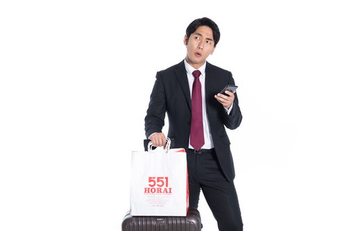 お土産に551の白い紙袋を持った会社員のビジネスマン