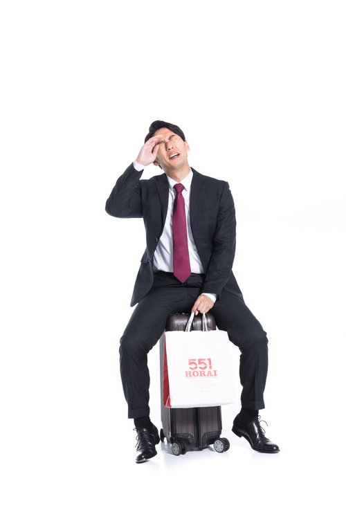 汗がとまらない大阪帰りの多忙な会社員、手土産のキャリーバッグを持ち疲労を見せる