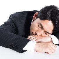 今年も働き詰めでやりきった会社員の机での寝落ちの写真