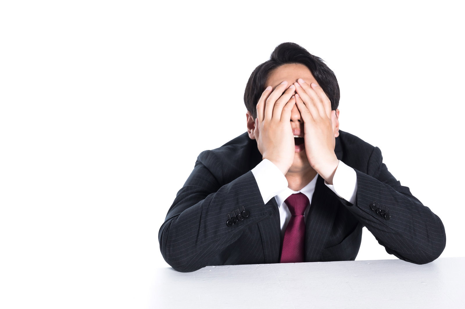 両手で顔を覆い頭を抱える黒いスーツ姿の男性会社員［モデル：大川竜弥］
