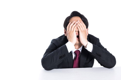 不正がバレて頭を抱える男性会社員のビジネストラブル