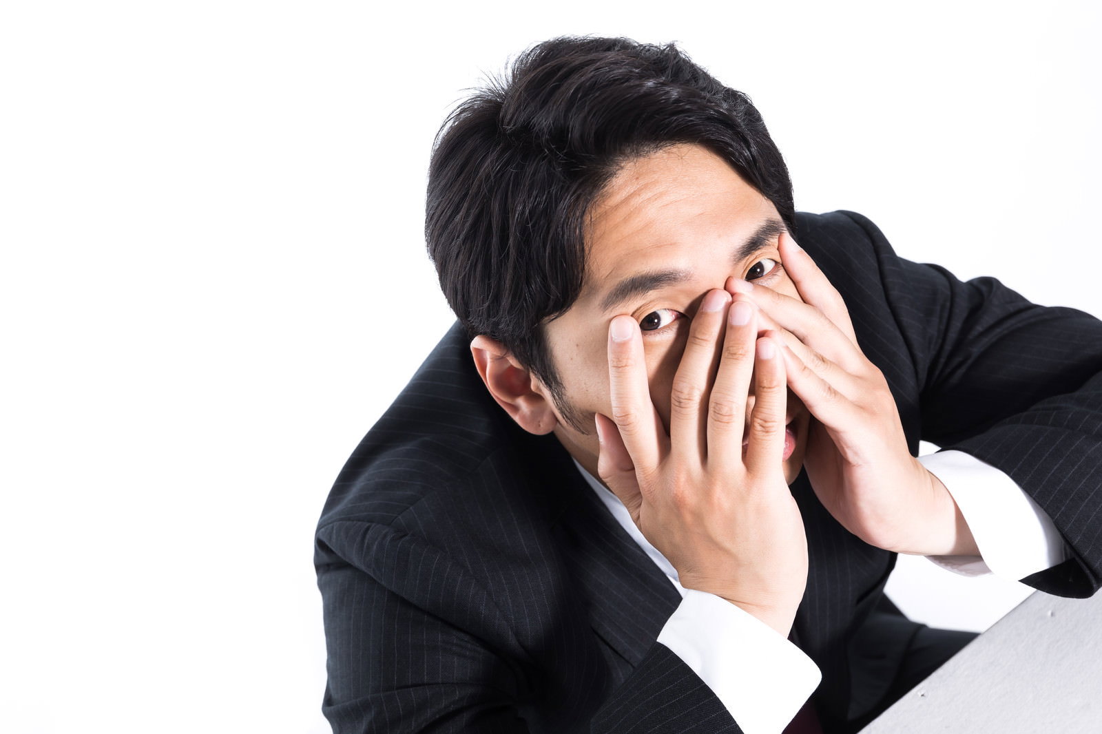 両手で顔を覆って疲労感を表現するスーツ姿の会社員男性［モデル：大川竜弥］