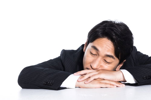 机に突っ伏して昼寝する会社員の疲労と休憩