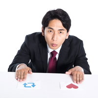 机の上の赤と青のカードで迷う会社員の意思決定の写真