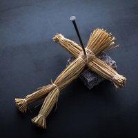 暗い背景に五寸釘が刺さった恨みを込められた藁人形の写真