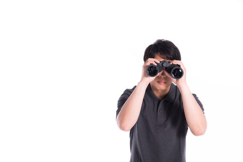 双眼鏡で監視する浮気調査中の探偵男性の監視風景