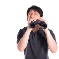 双眼鏡で監視中にハプニングを見つけた瞬間の男性の写真