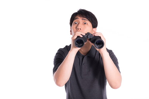 双眼鏡で監視中にハプニングを見つけた瞬間の男性